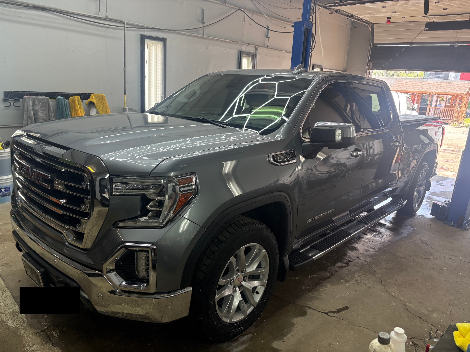 Grey GMC Sierra SLT driver-side three-quarter, glossy paint reflecting hex lights