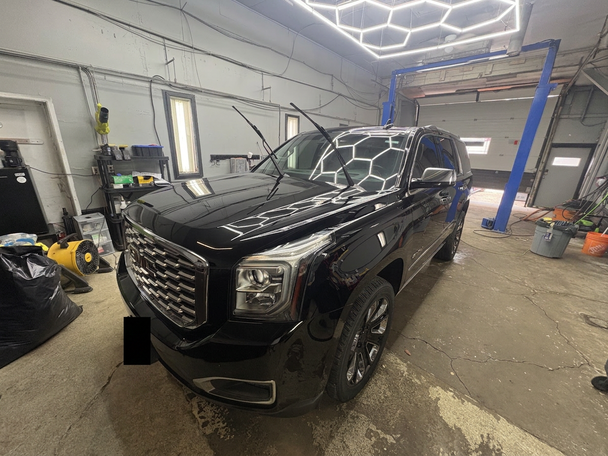 Black GMC Yukon Denali front three-quarter under hex lights